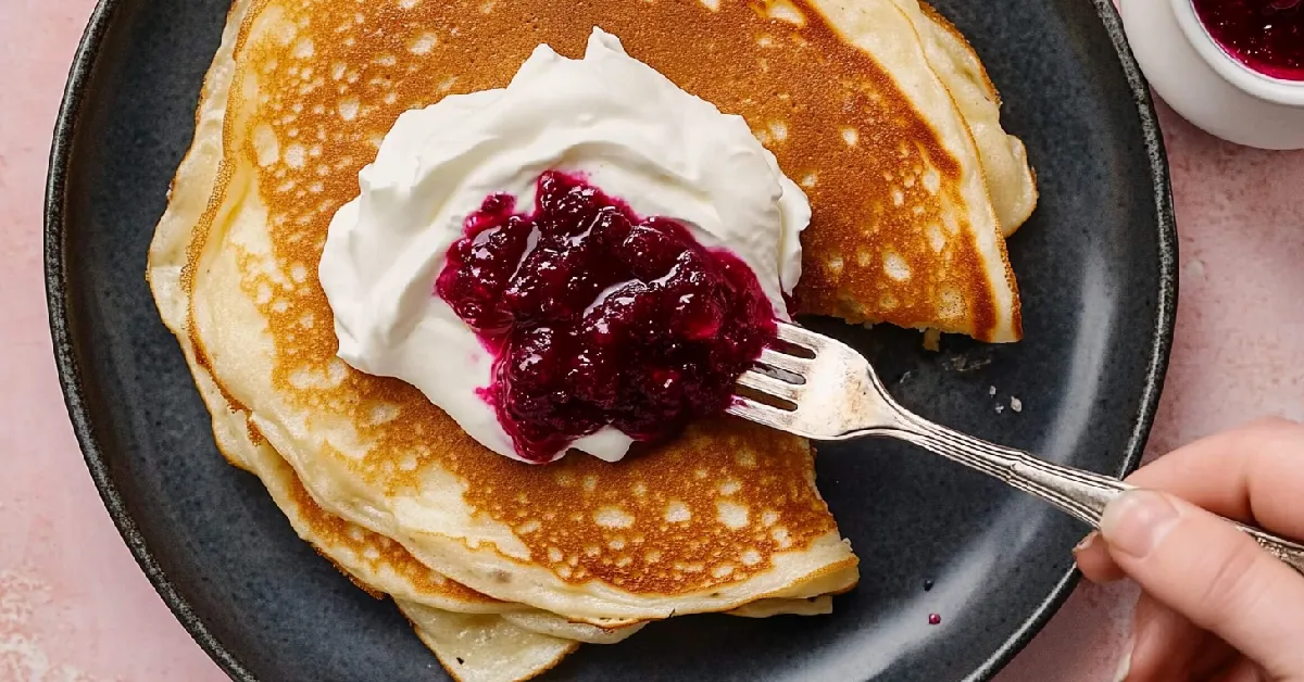 Swedish Pancakes with Lingonberry Jam and Cream on a Dark Plate